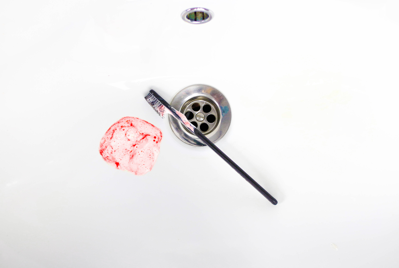 Toothpaste with blood in a ceramic sink. Bleeding gums. Close up